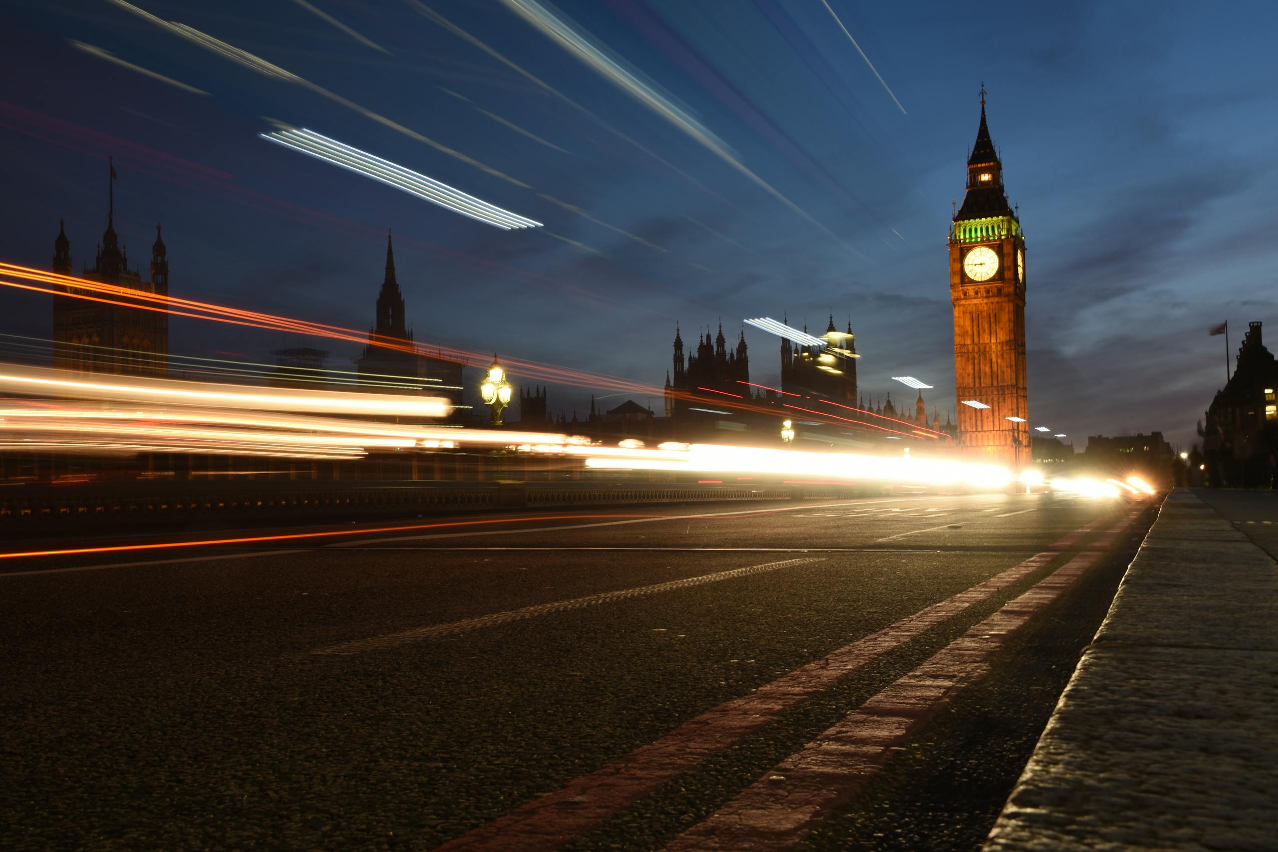 Captivating long exposure photograph of Big Ben with light trails from traffic at night in London.